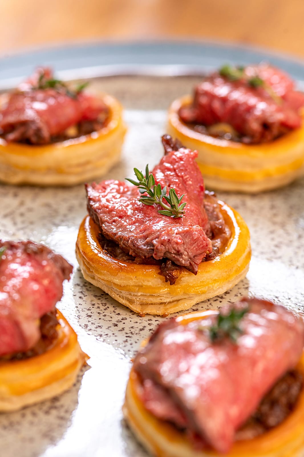 Canapés com carne rosada e alecrim sobre massa folhada dourada