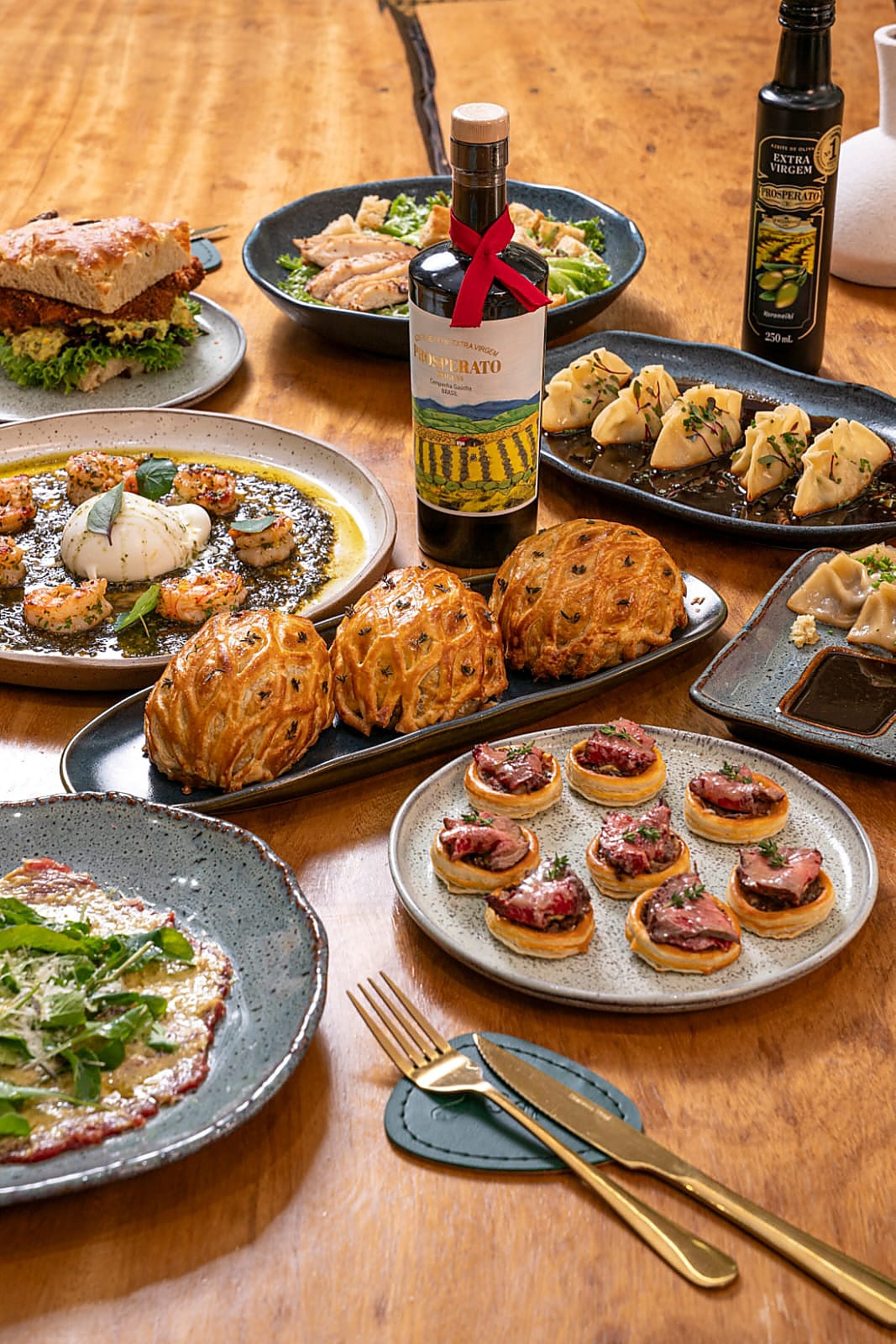Mesa com diversos pratos do Empório Sálvia, incluindo massas folhadas e canapés
